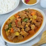 Pork Menudo on a serving platter with a side of steamed rice