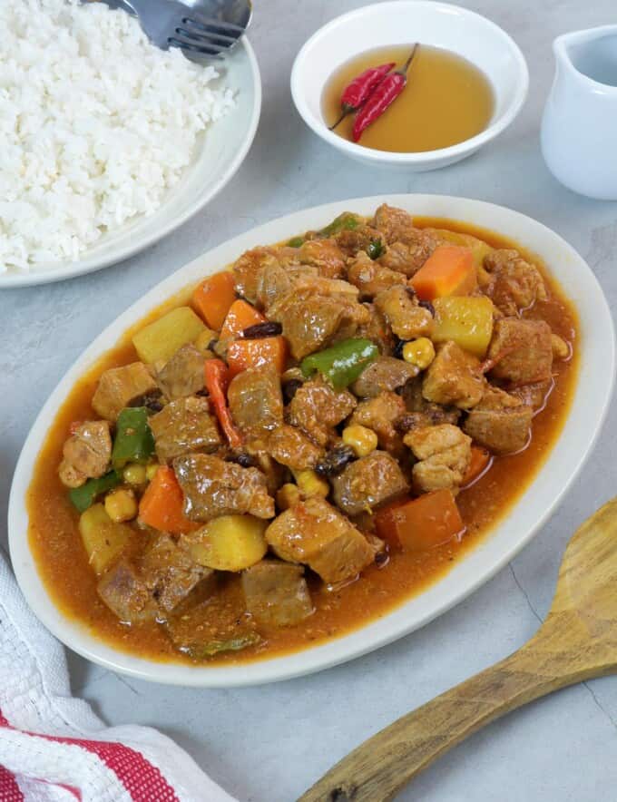 Pork Menudo on a serving platter with a side of steamed rice