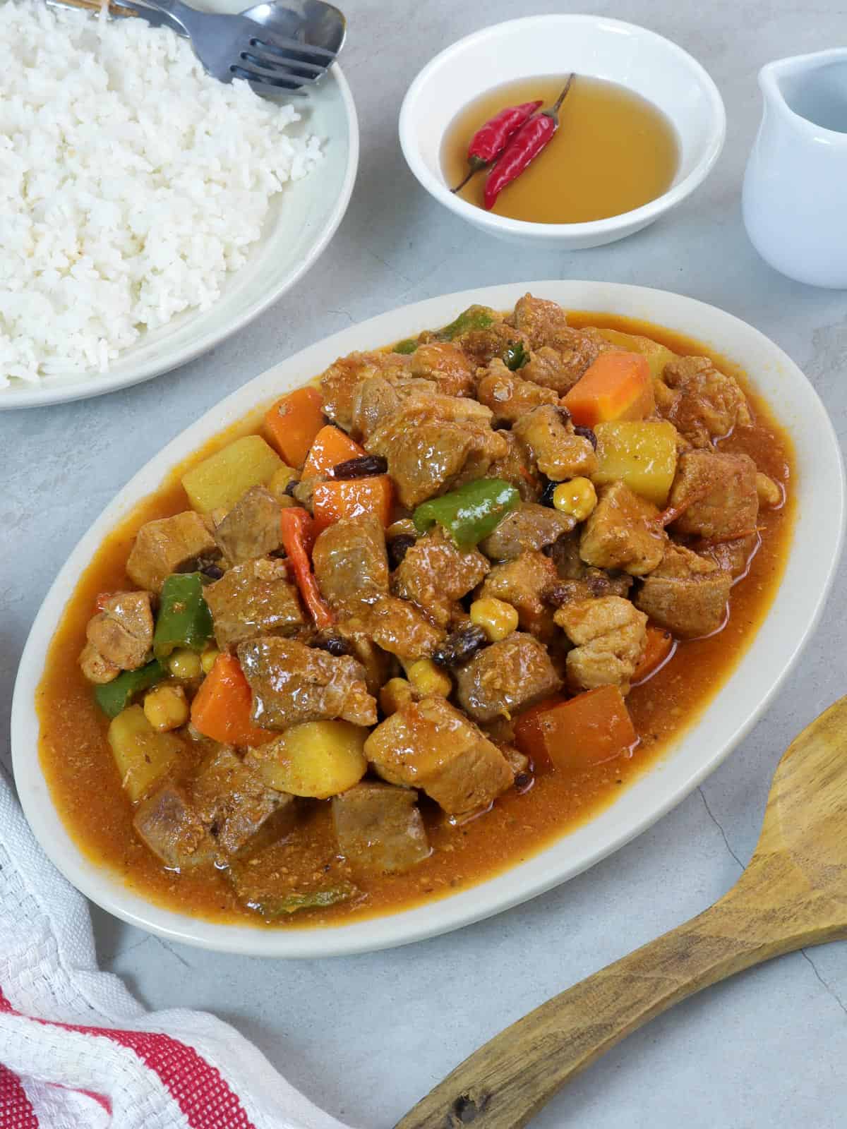 Pork Menudo on a serving platter with a side of steamed rice