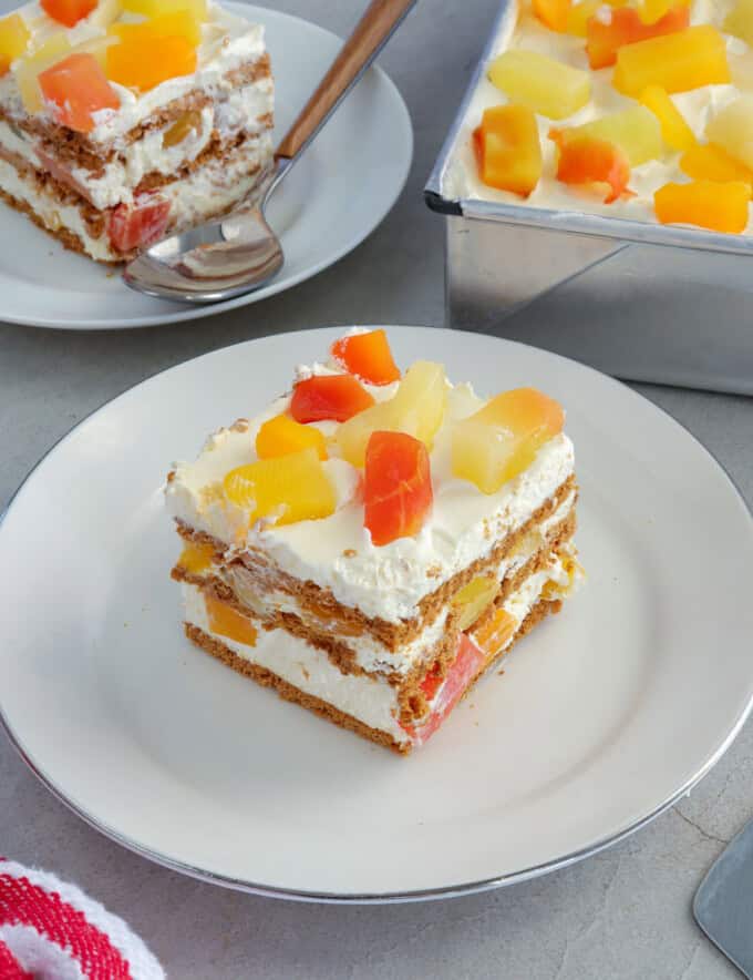 slice of no-bake fruit cocktail graham cake on a white plate.