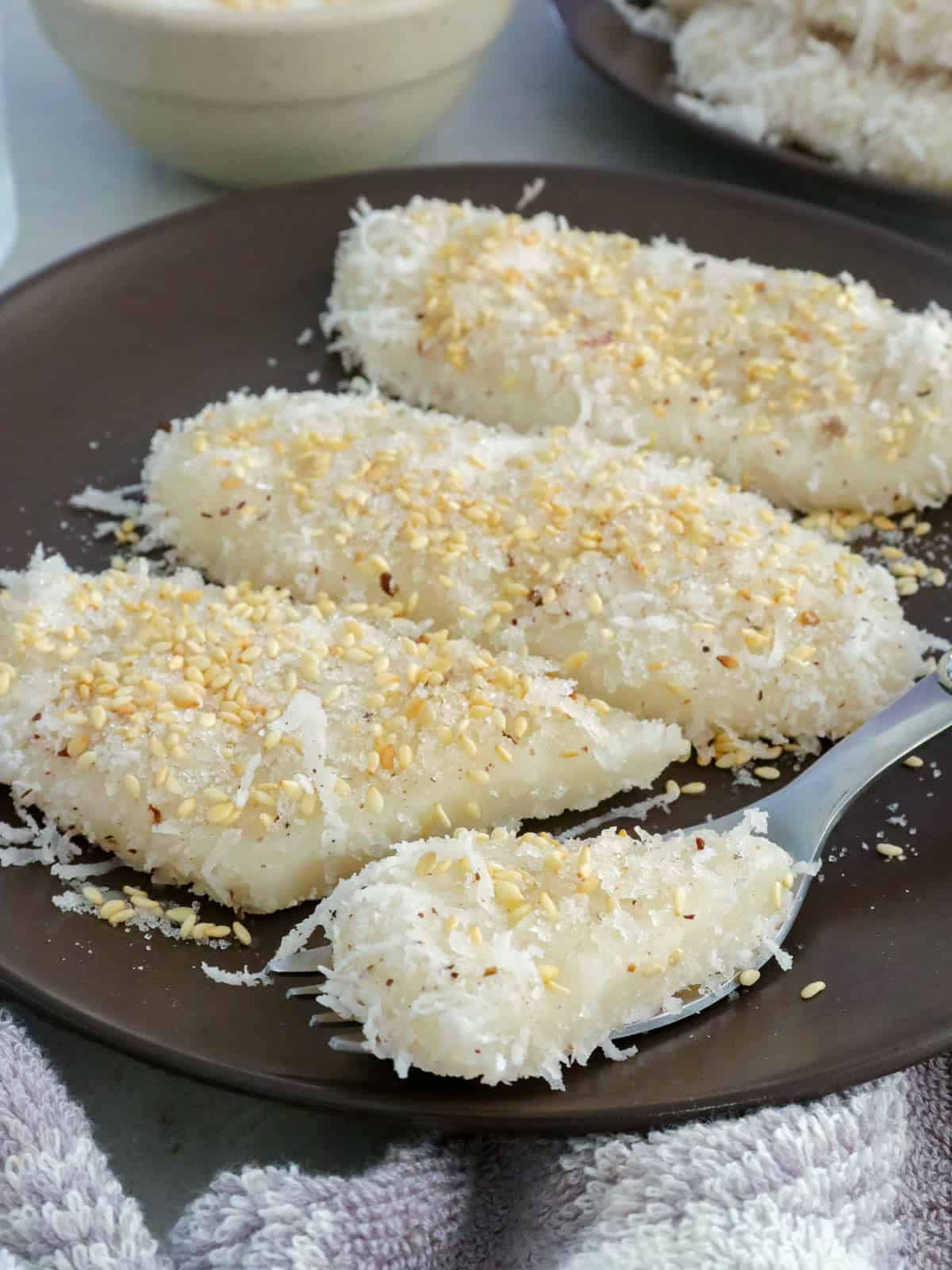 eating palitaw with a fork on a plate