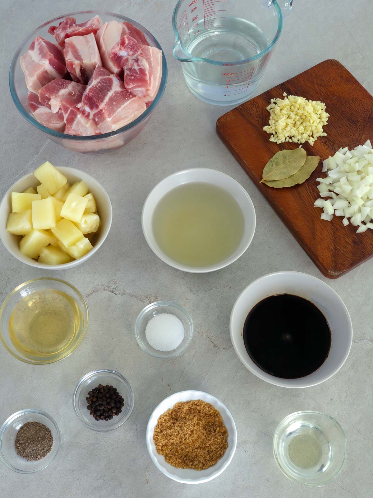 pork belly, pineapple juice, pineapple chunks, garlic, onions, bay leaves, oil, brown sugar, apple cider vinegar, pepper, salt in bowls