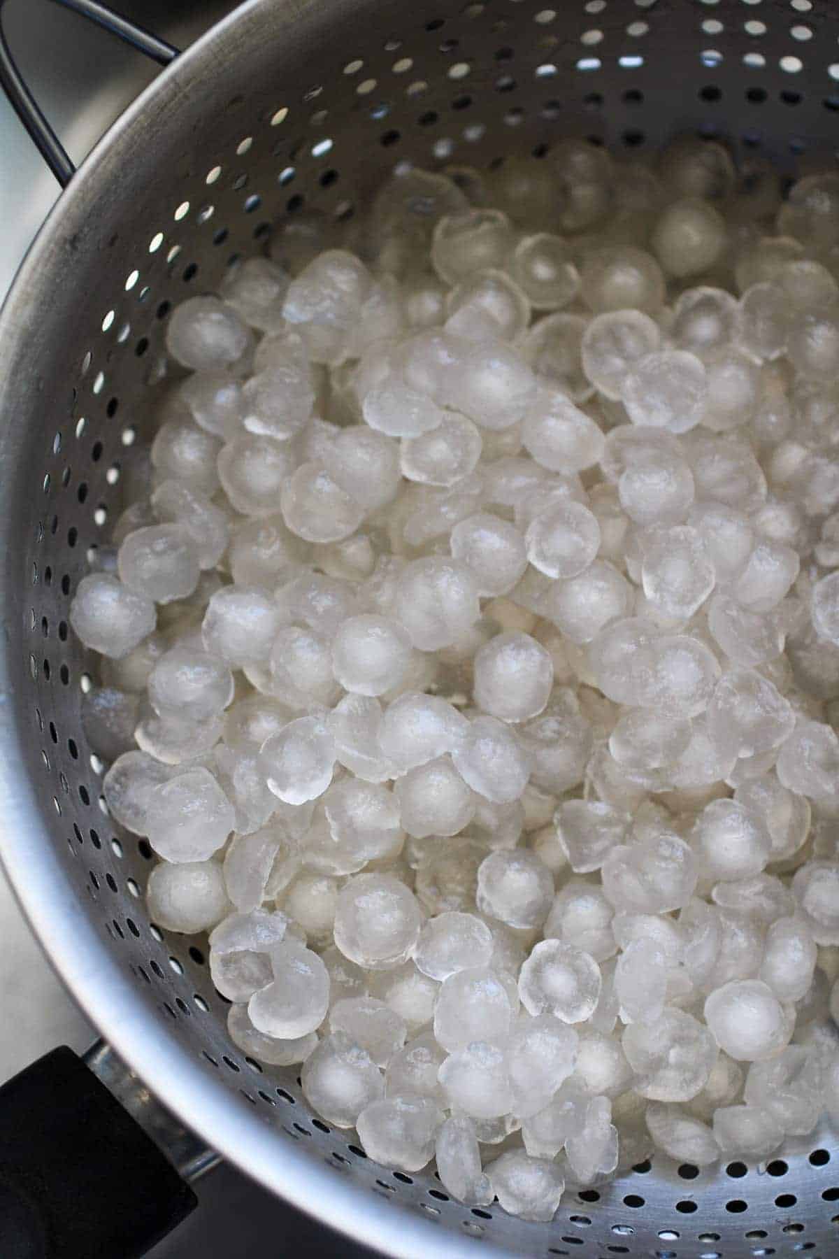 draining cooked sago in a metal colander