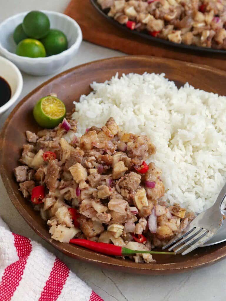 Sizzling Sisig with steamed rice on a wooden plate