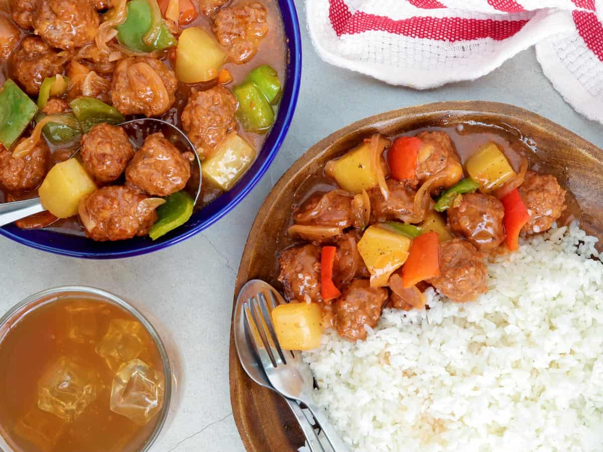 sweet sour meatballs with steamed rice on a wooden plate