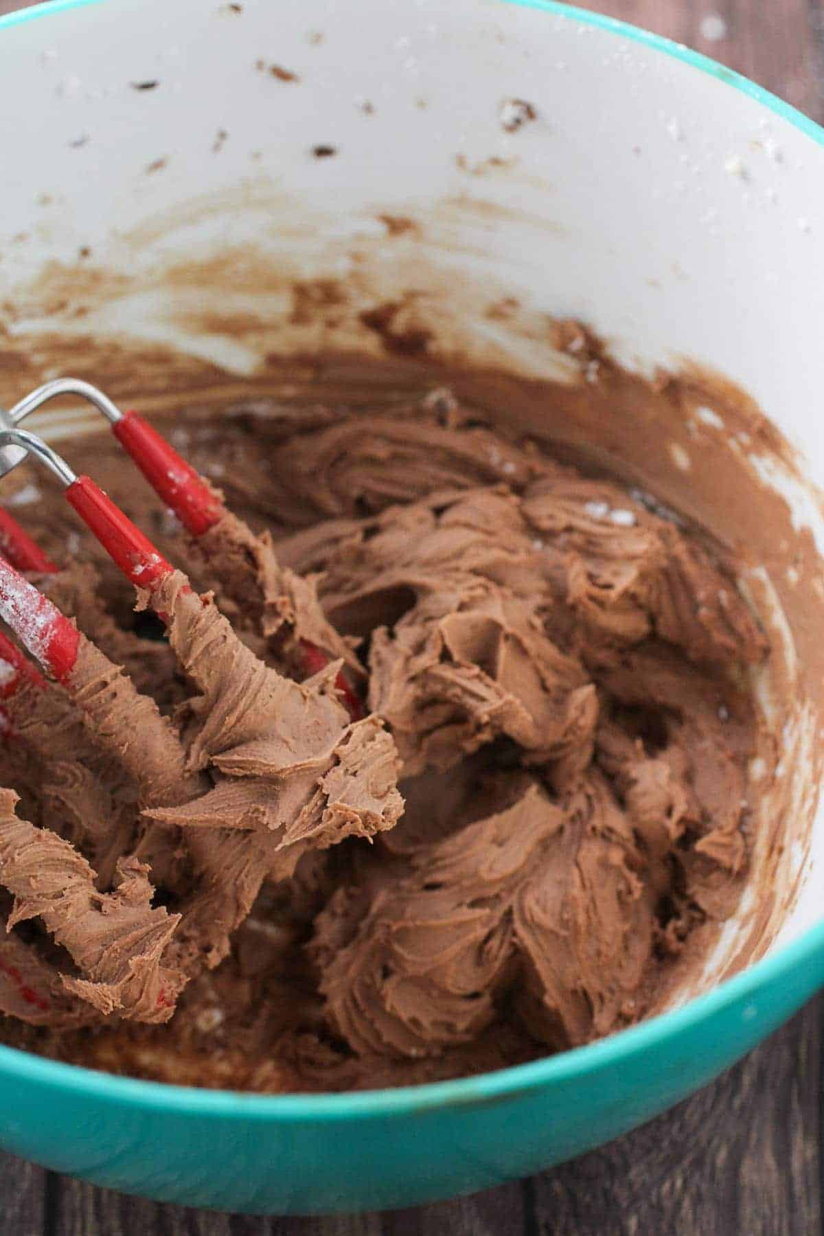 making mocha buttercream frosting in a blue bowl