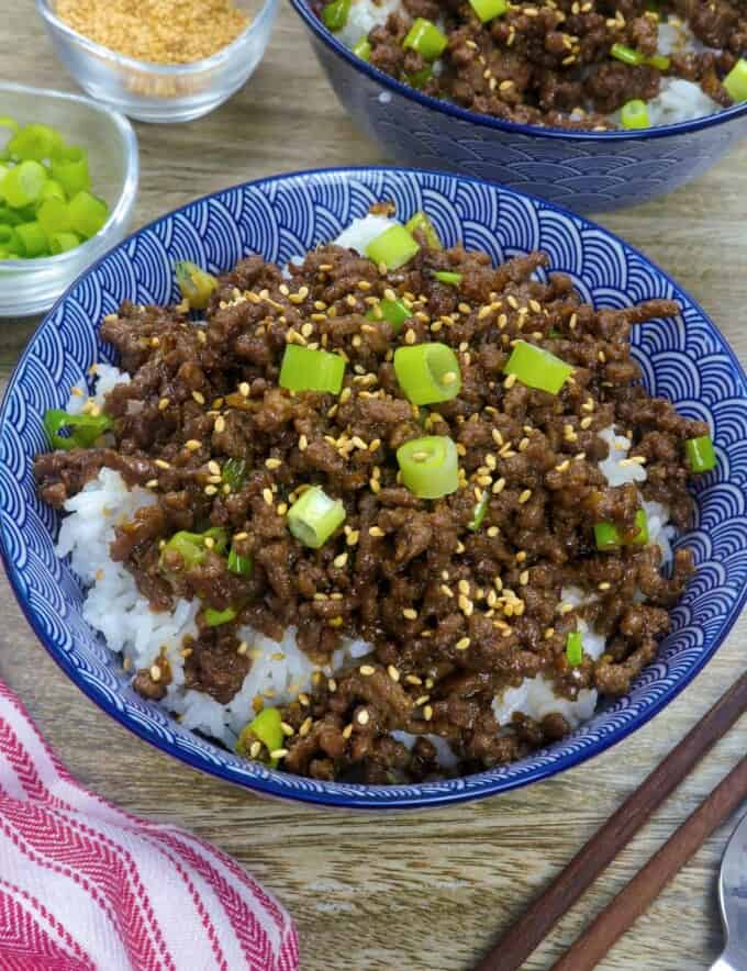 Korean Ground Beef on a bed of steamed rice garnished with green onions and sesame seeds in white serving bowl