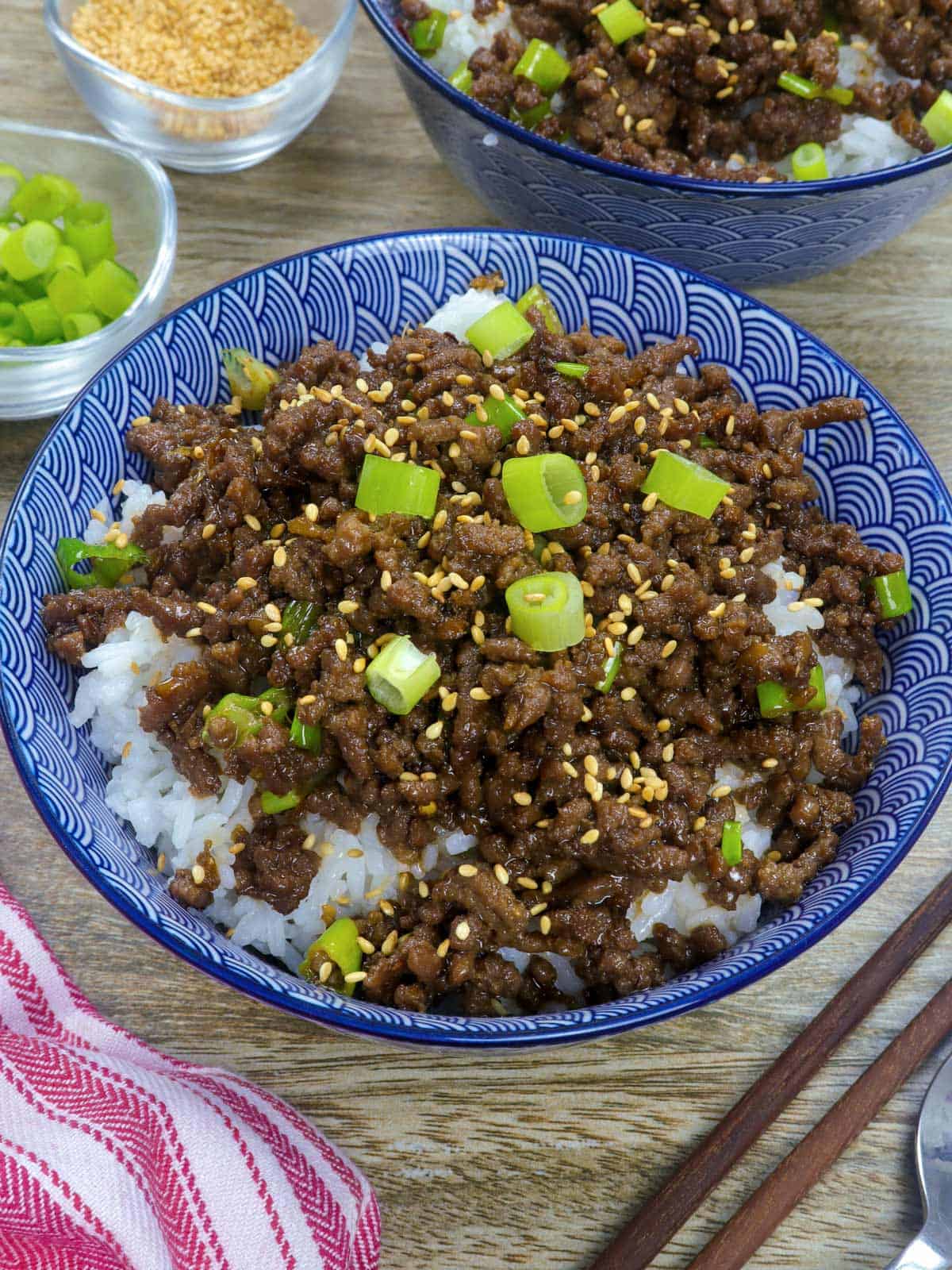 Korean Ground Beef on a bed of steamed rice garnished with green onions and sesame seeds in white serving bowl