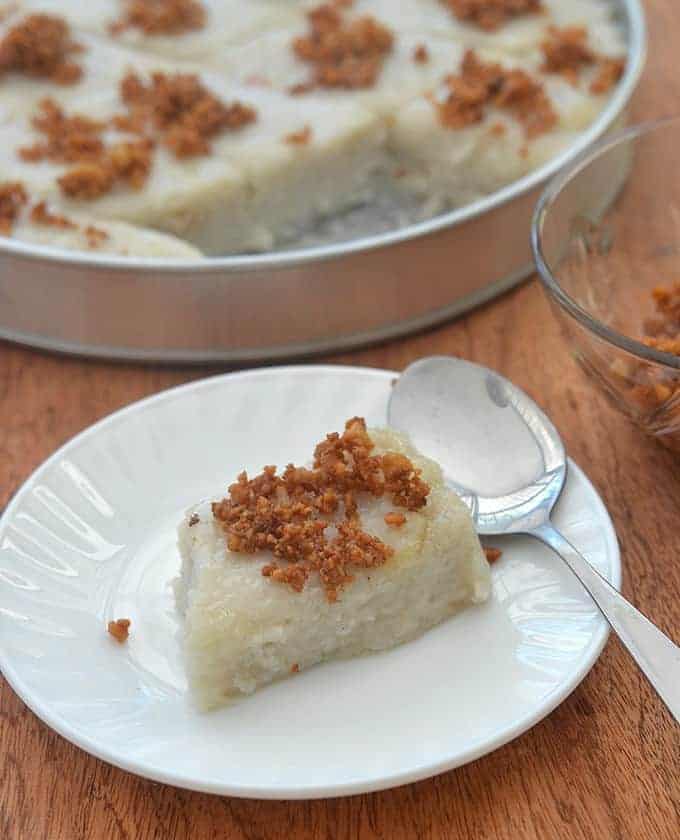 This tasty slice of Filipino rice caked is served with a spoon and topped wit crispy brittle. 