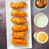 top view of southwestern chicken egg rolls on a white platter with dipping sauce on the side