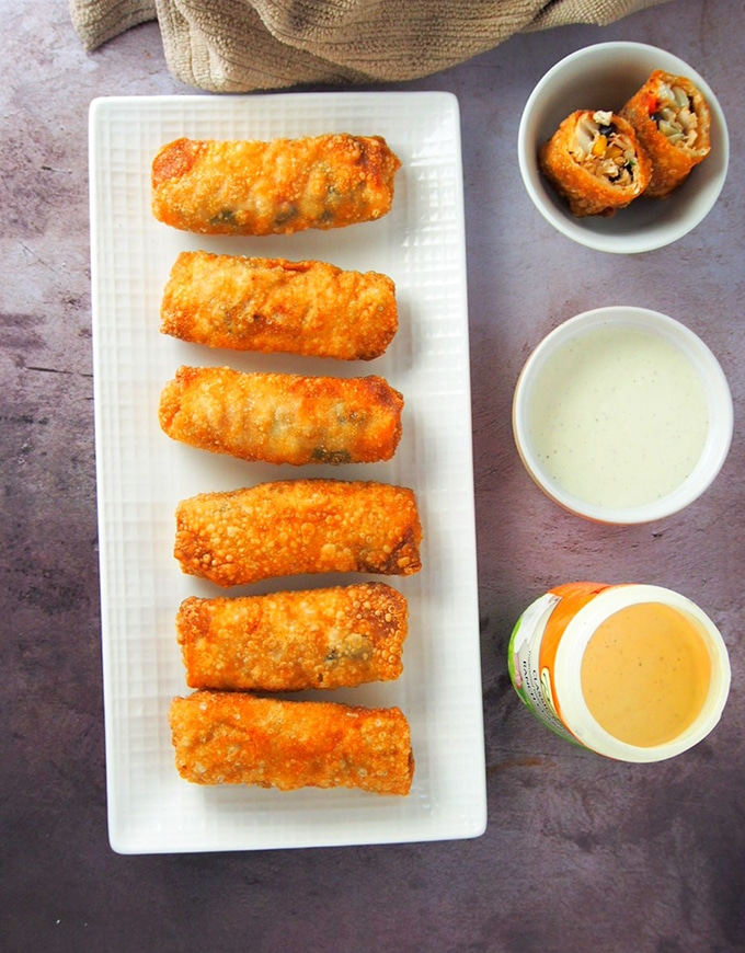 top view of southwestern chicken egg rolls on a white platter with dipping sauce on the side