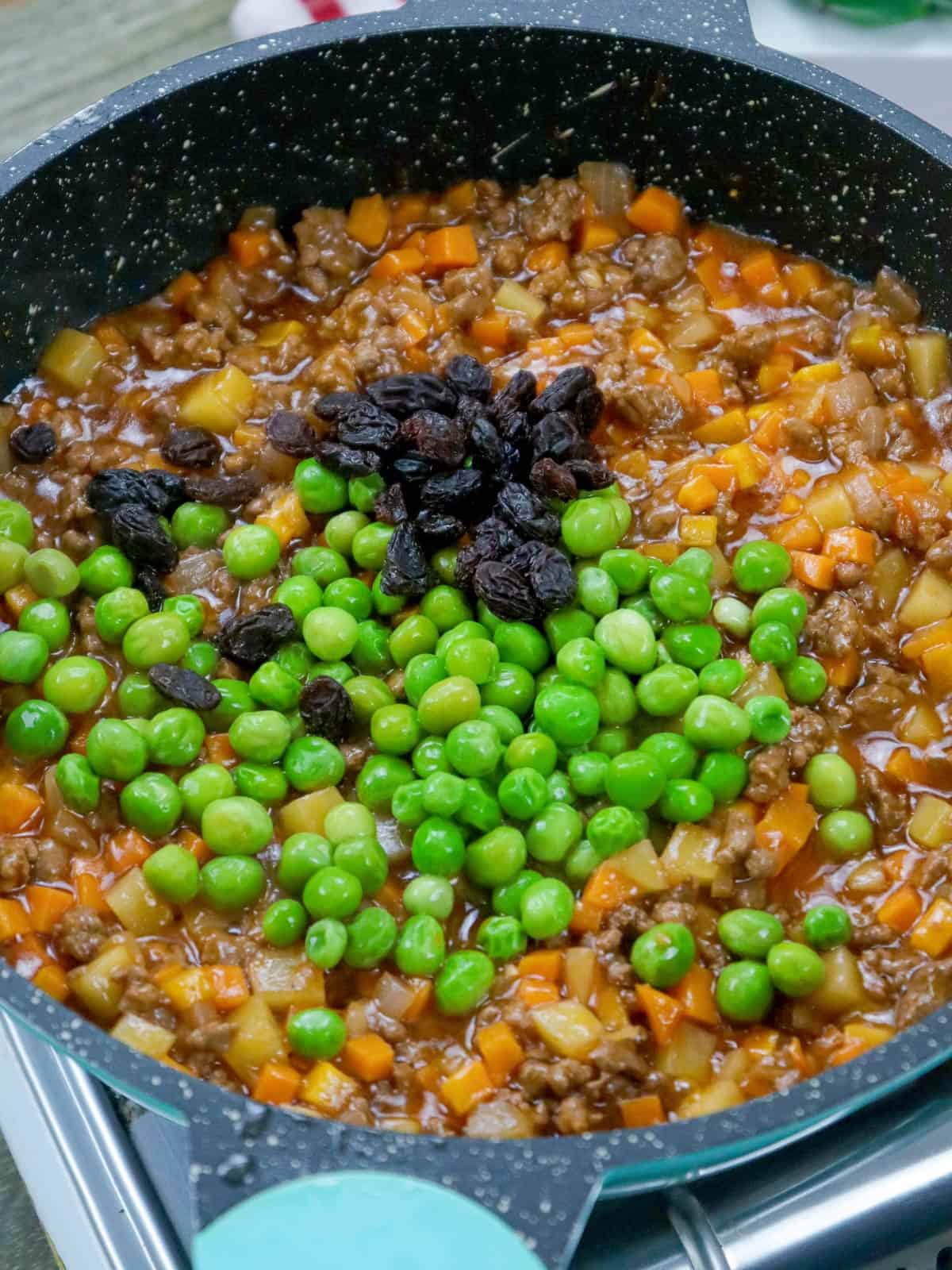 beef giniling filling in a pan with raisins and green peas