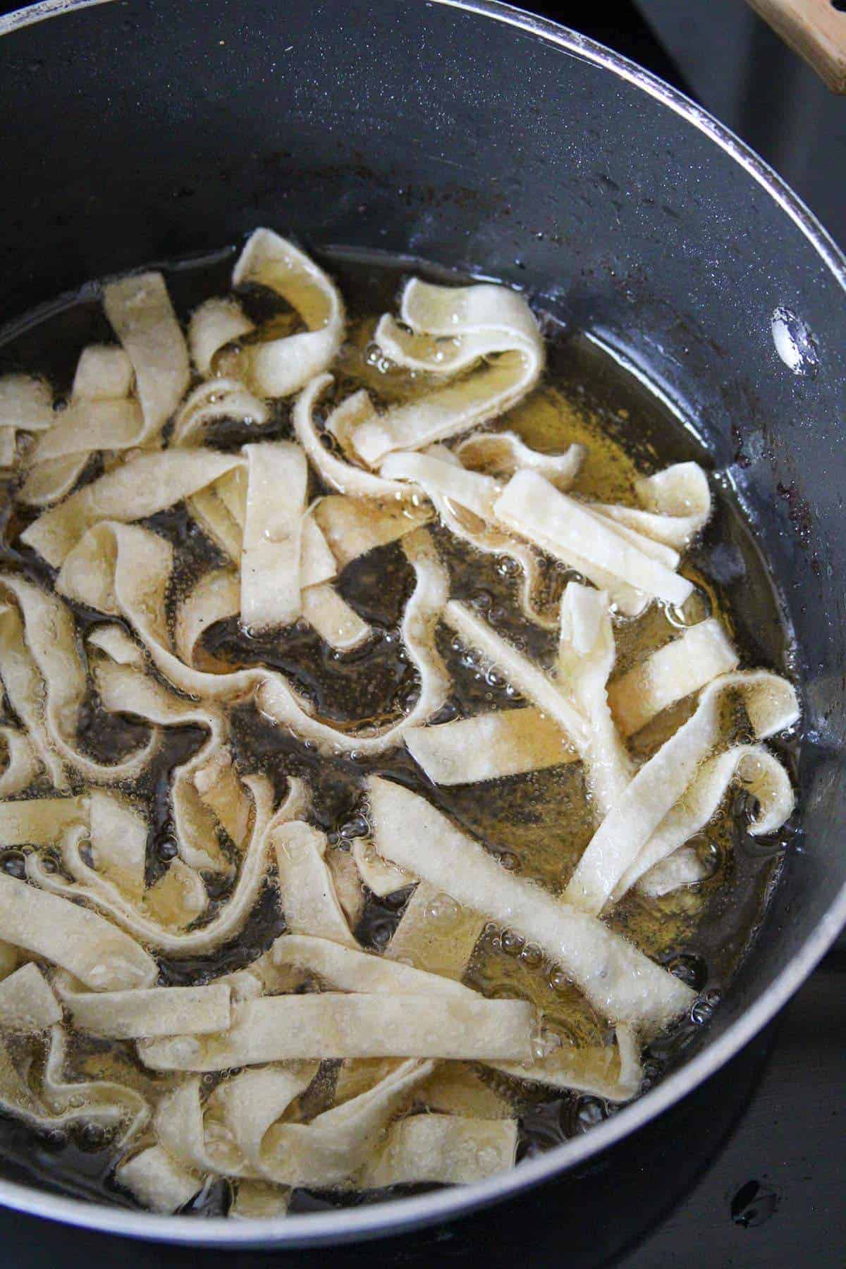 frying wonton strips in a hot oil in a pot