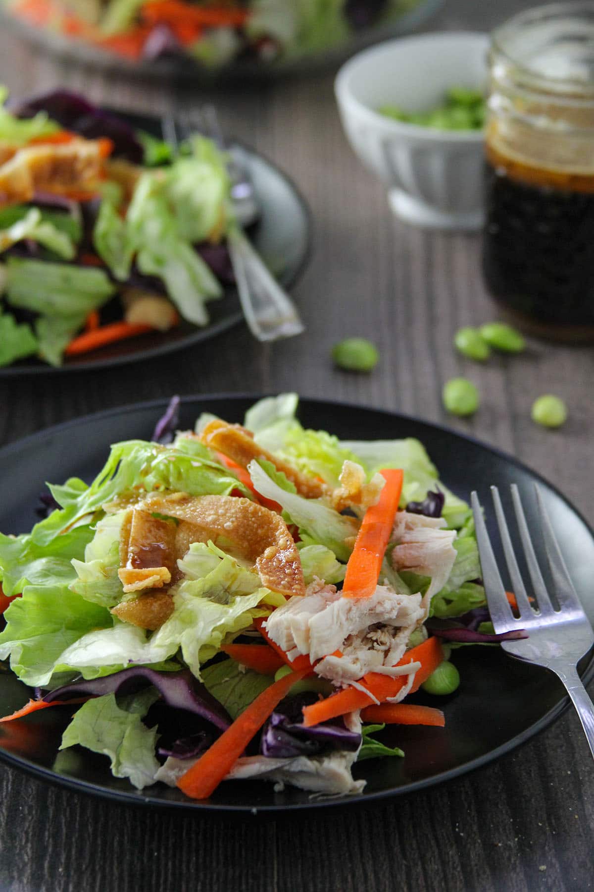 Chinese Chicken Salad on a black serving plates with salad dressing on the side