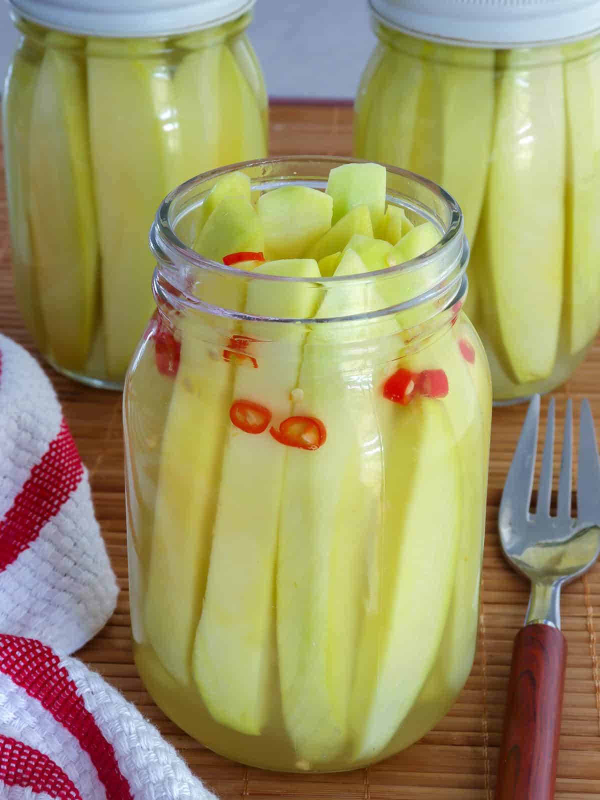 Pickled Mangoes with chili pepper in glass jar