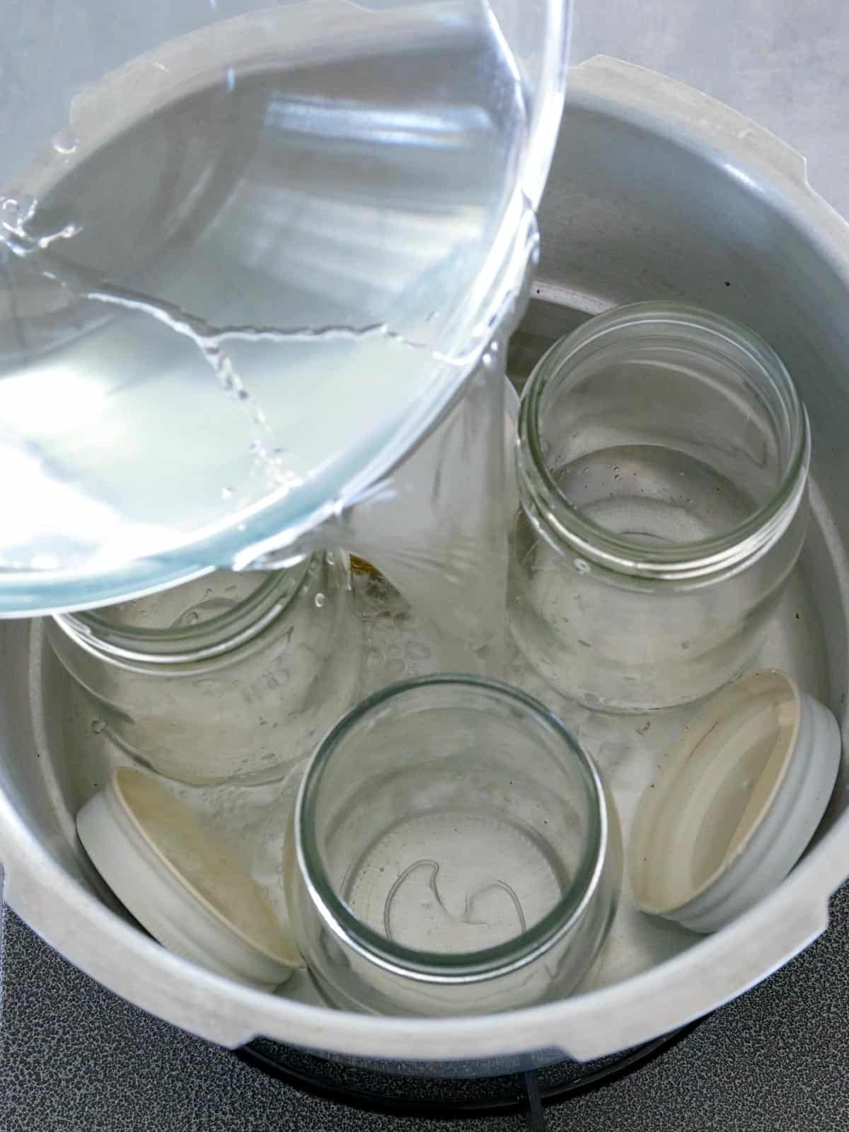 pouring water into a pot of mason jars