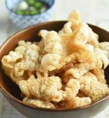 Pork Chicharon in a wooden serving bowl with a side of spicy vinegar