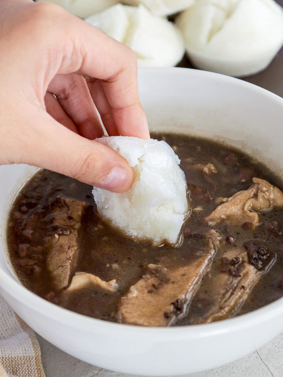 dipping putong bigas in a bowl of dinuguan.