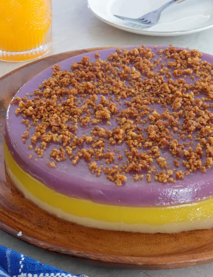 Sapin-Sapin with latik topping on a wooden plate.