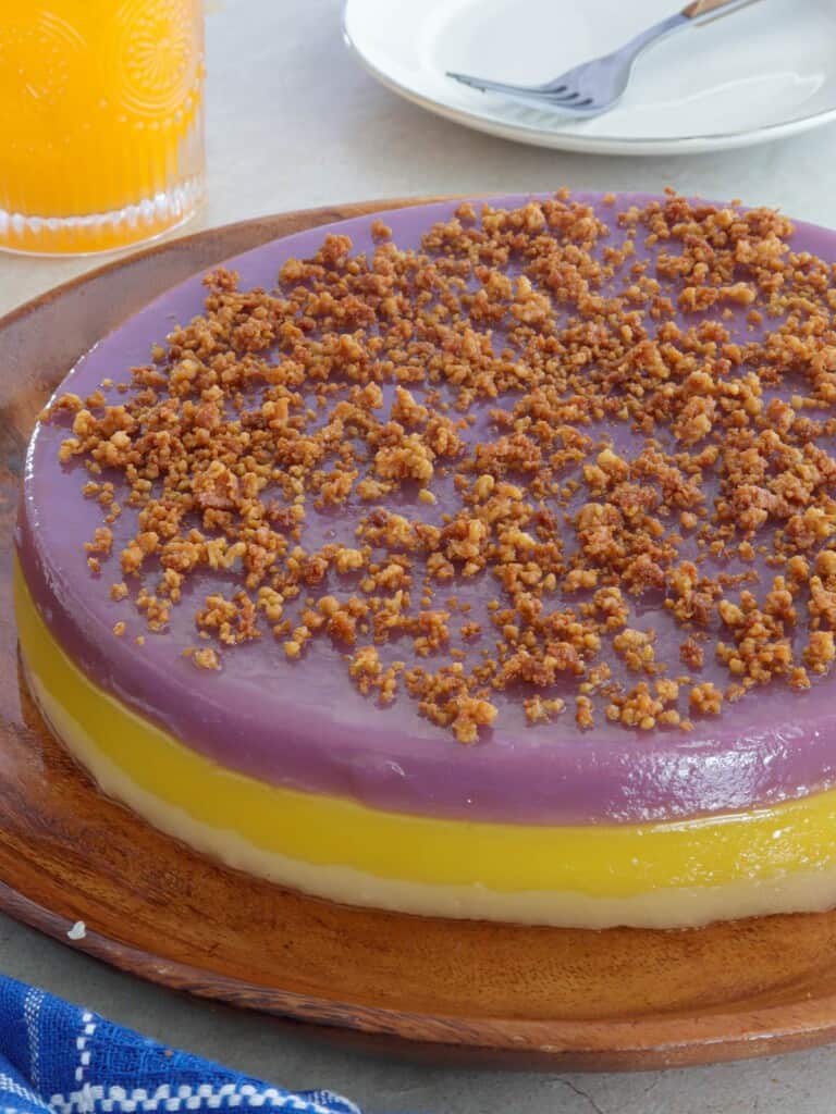 Sapin-Sapin with latik topping on a wooden plate.