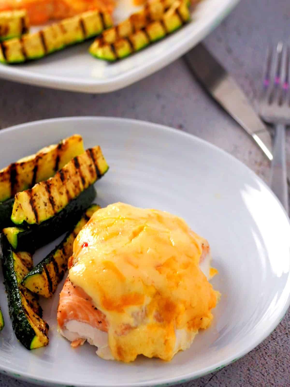 Baked Salmon with Sweet Chili-Mayo Topping on a white plate with grilled zucchini