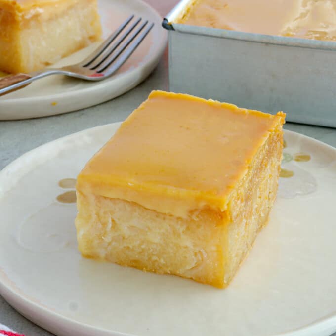 slice of cassava cake with custard topping on white serving plate.