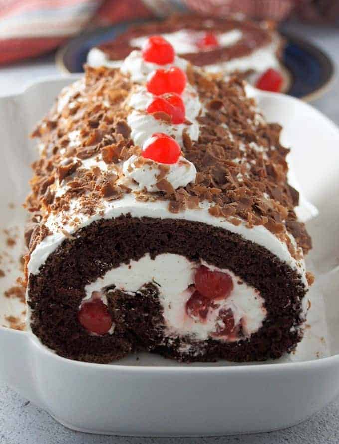Black forest swiss roll with whipped cream, cherries, and chocolate shavings