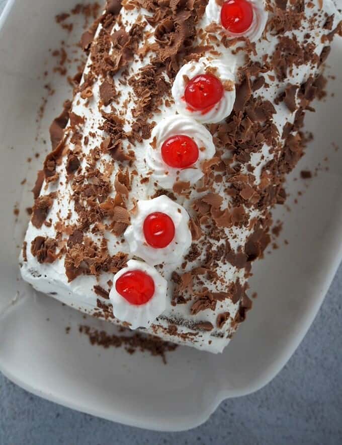 top view of a Black Forest Swiss Roll Cake on a white serving platter