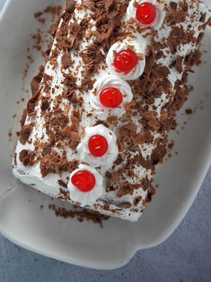 top view of a Black Forest Swiss Roll Cake on a white serving platter