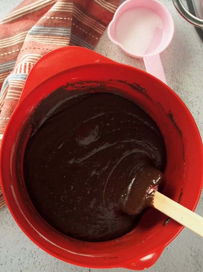 melted chocolate and cocoa powder in a red bowl with a spatula