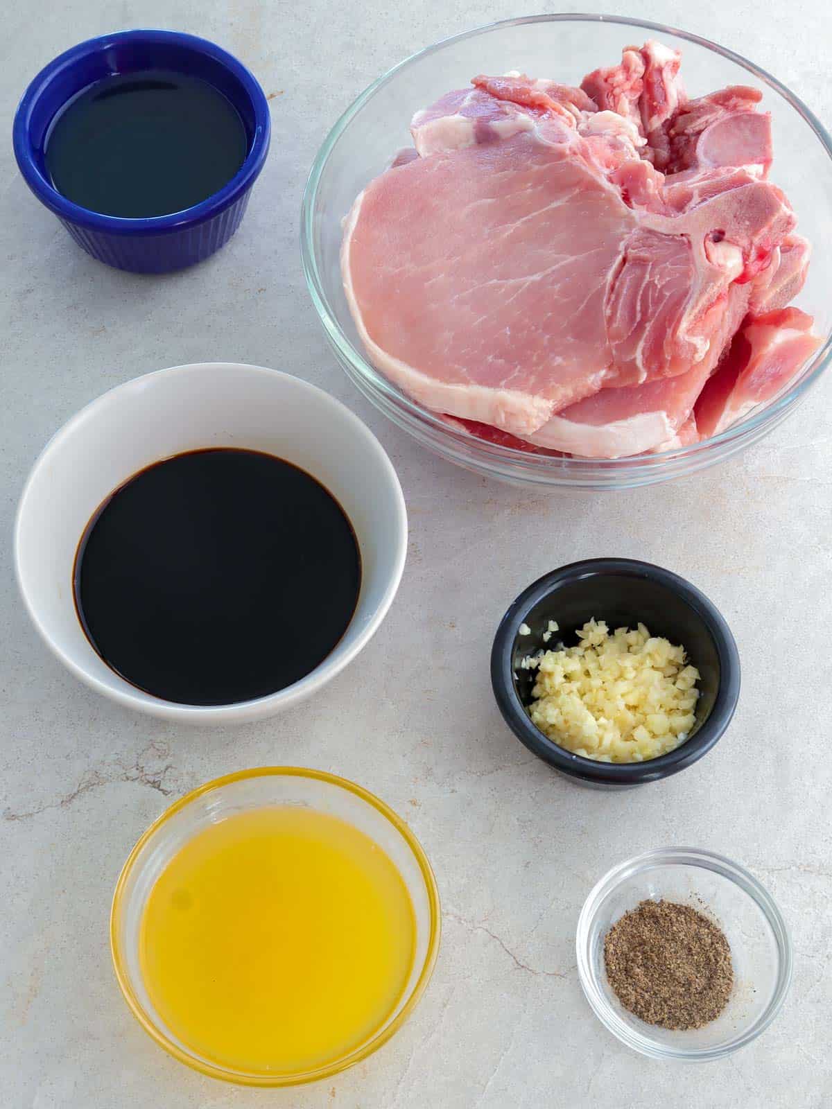 calamansi juice, minced garlic, soy sauce, pork chops, pepper, oil in bowls