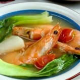 sinigang na hipon with pak choi, radish, and calamansi in a white serving bowl with a side of steamed rice