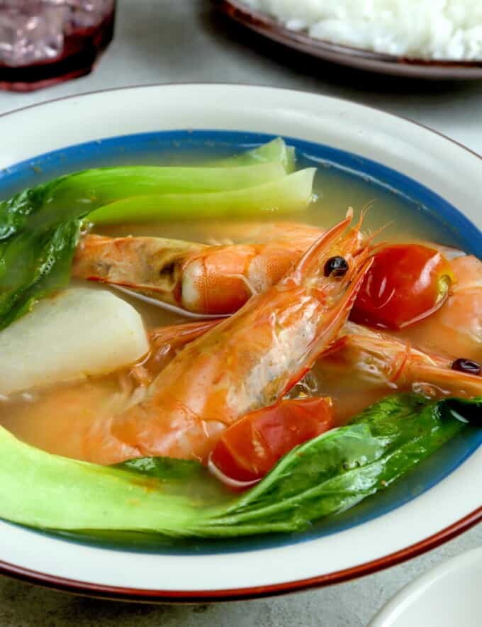 sinigang na hipon with pak choi, radish, and calamansi in a white serving bowl with a side of steamed rice