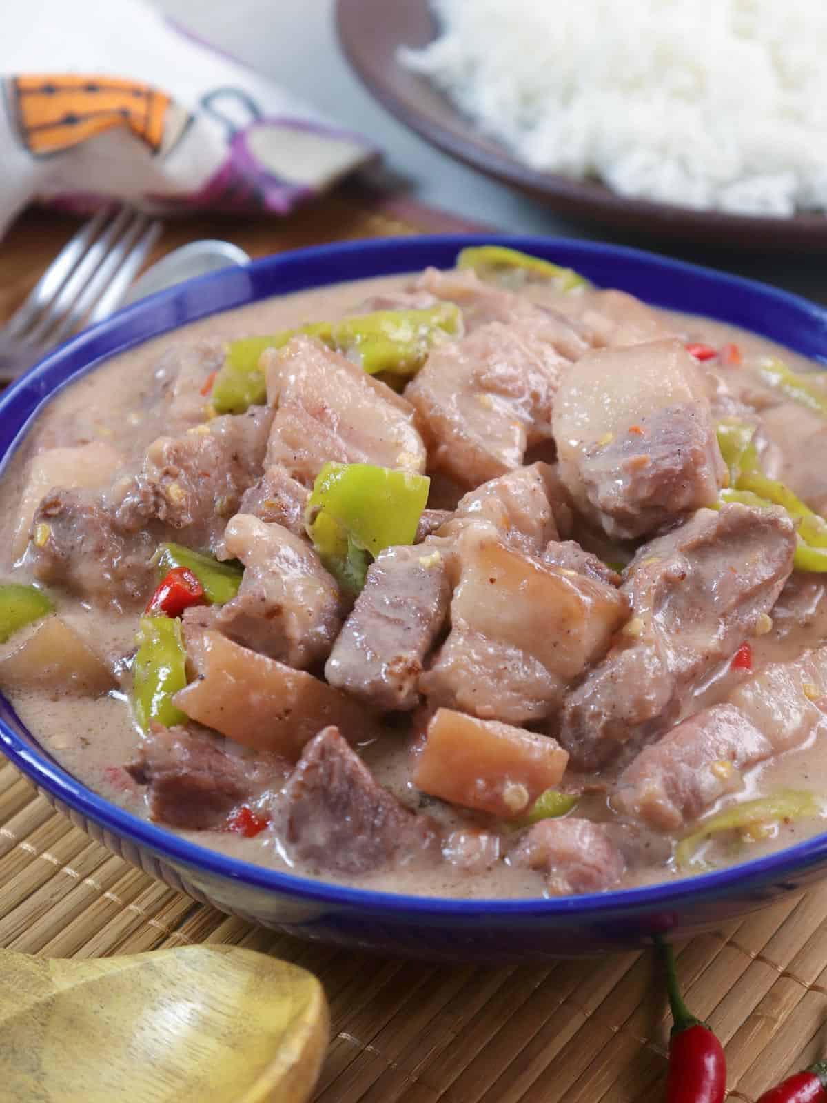 creamy pork stew with coconut milk and chili peppers in a blue serving bowl