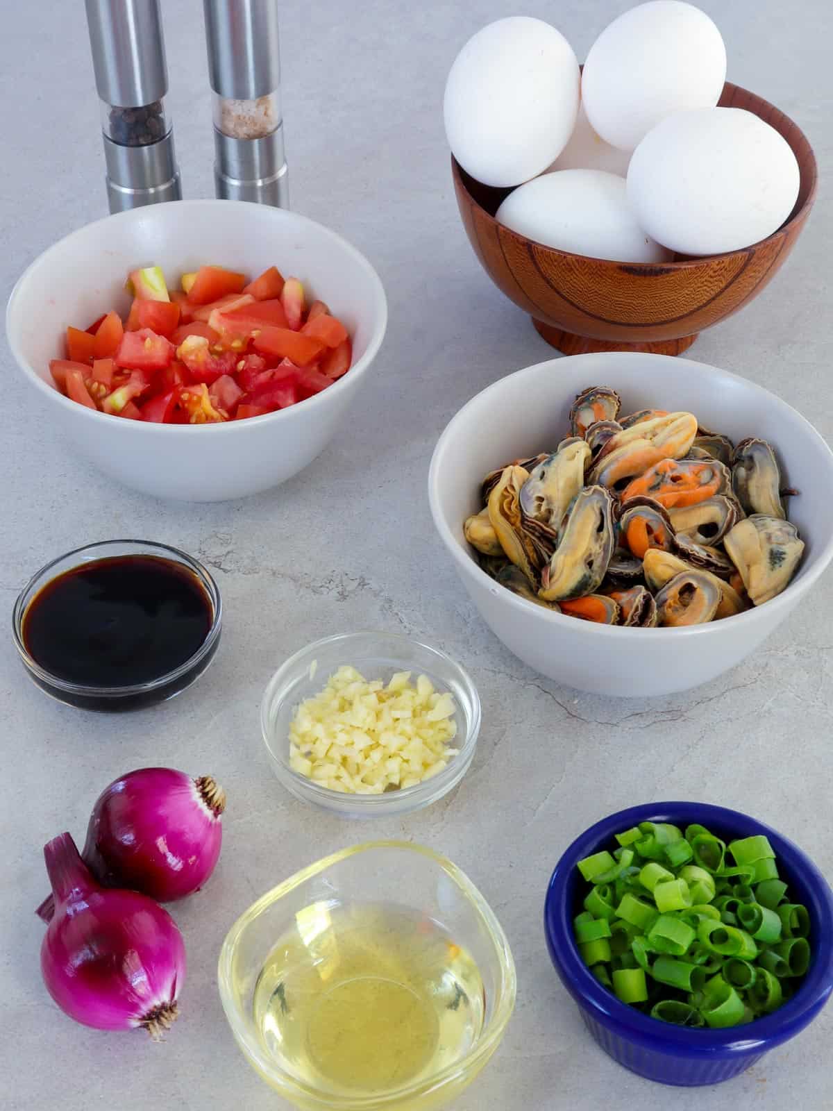 mussel meat, tomatoes, eggs, green onions, onions, garlic, oyster sauce, oil in bowls, and salt and pepper shakers