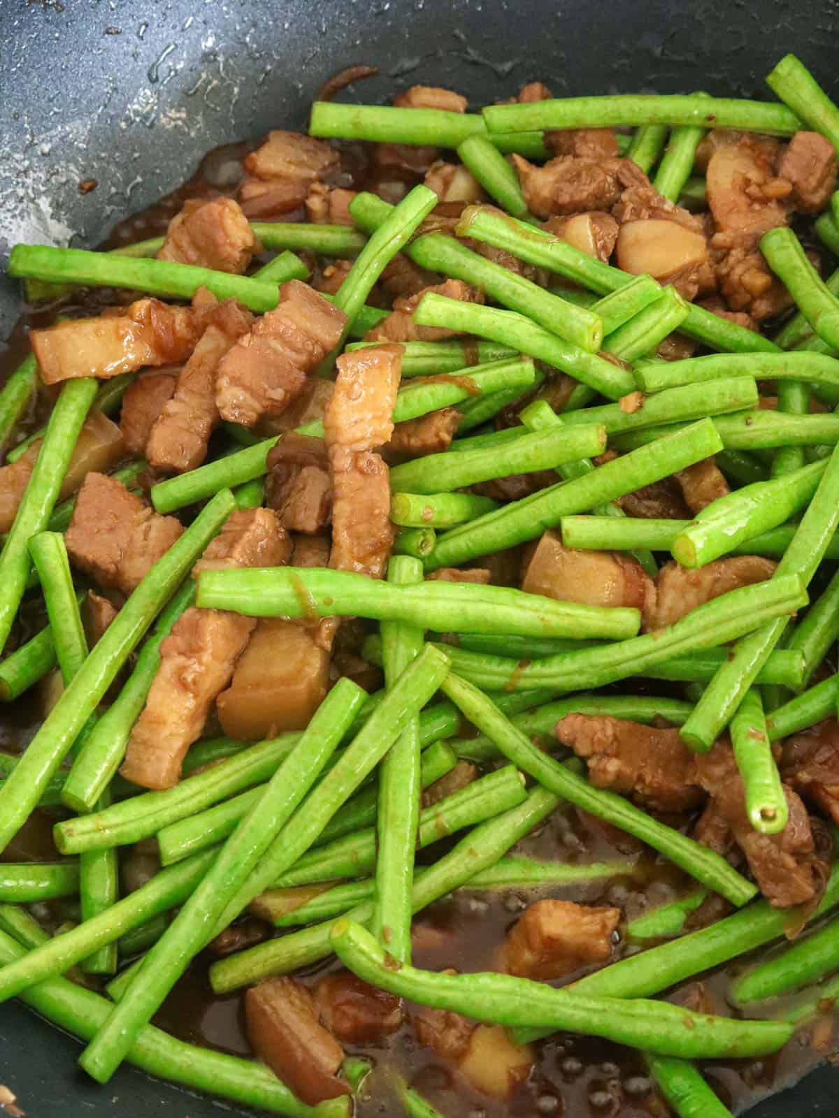long beans adobo with pork bely in a pan.