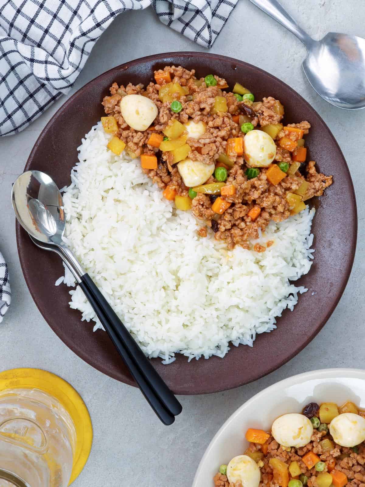 Pork Giniling with Quail Eggs over steamed rice on a brown plate