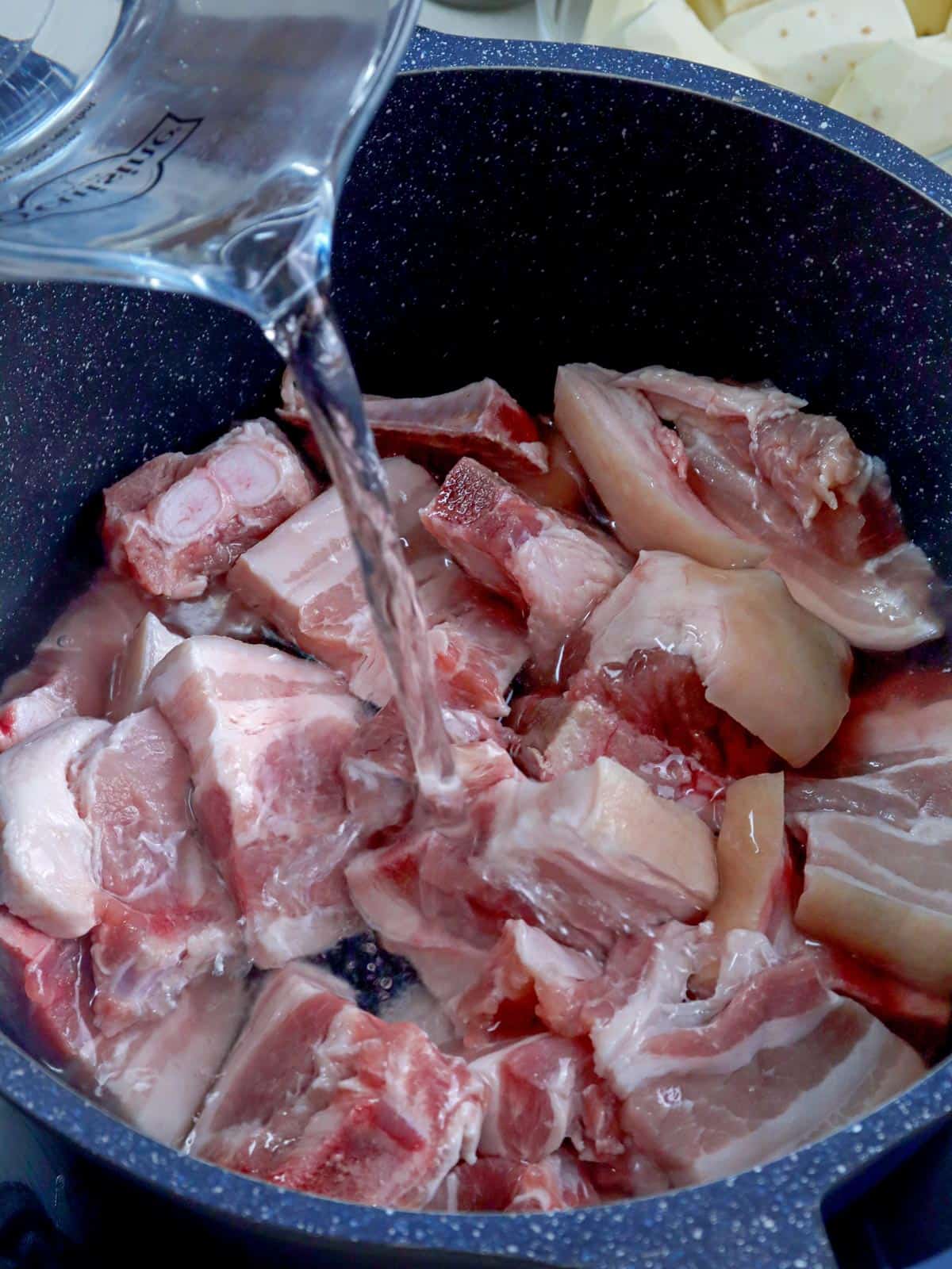 pouring water to a pot of pork