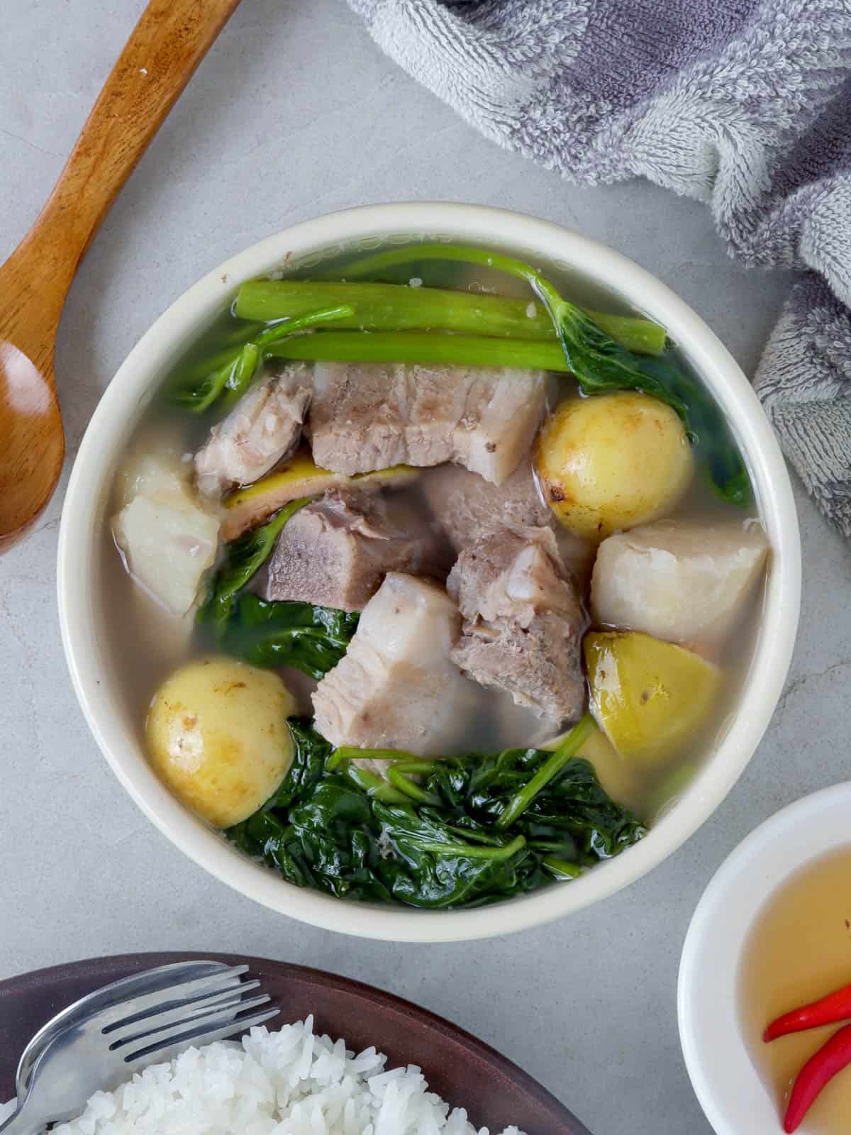 sinigang na baboy sa bayabas in a white bowl and a plate of steamed rice on the side