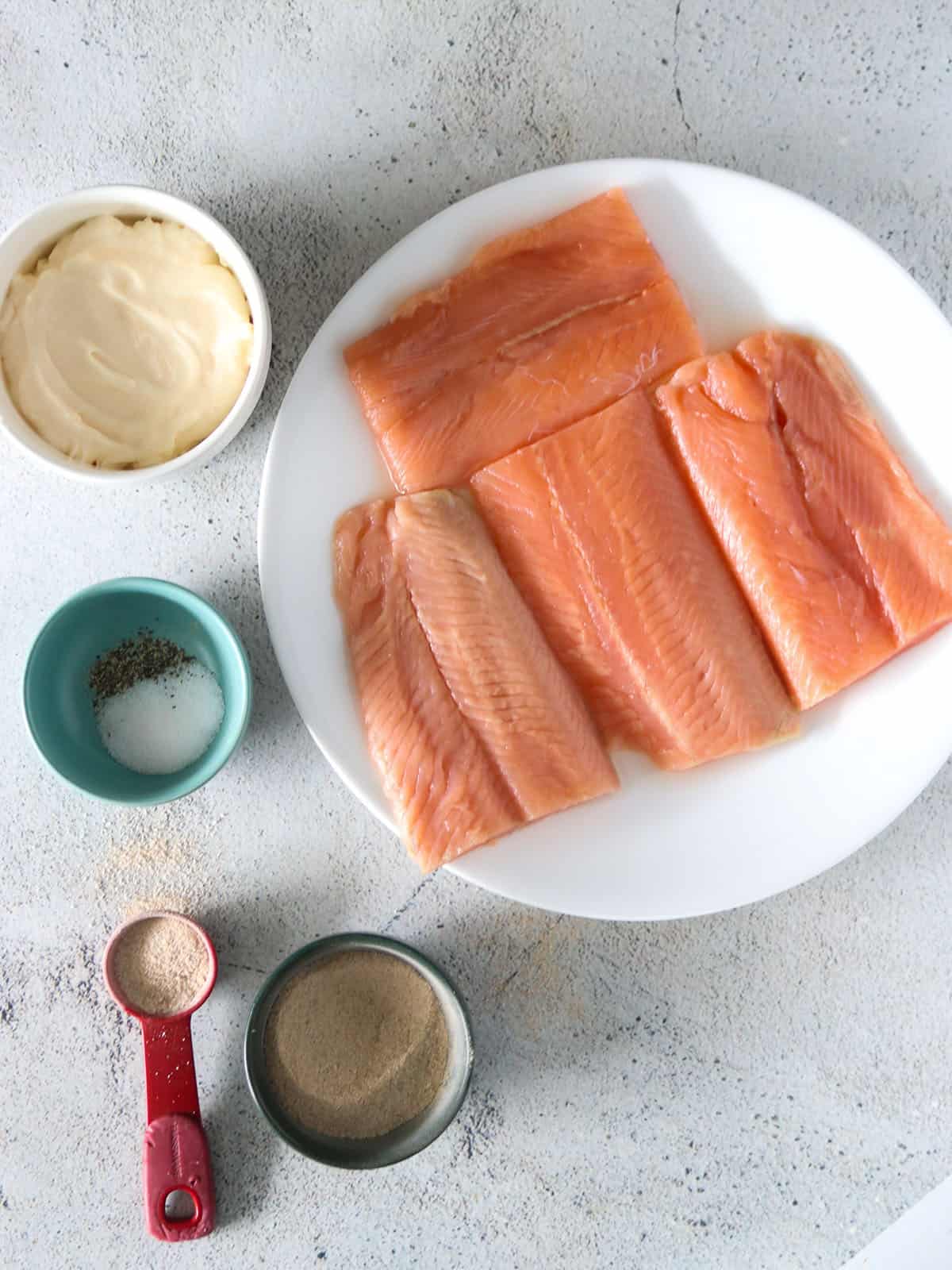 raw salmon fillet on a white plate with tamarind powder and mayonnaise on the side