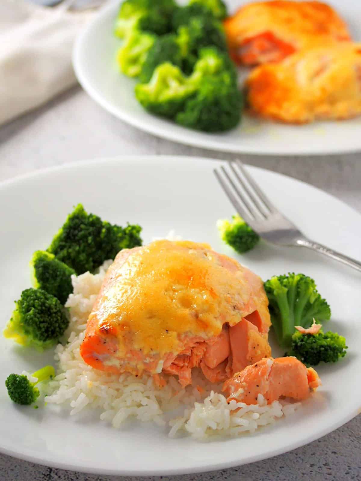 baked salmon with mayo topping on top of steamed rice with steamed broccoli on the side