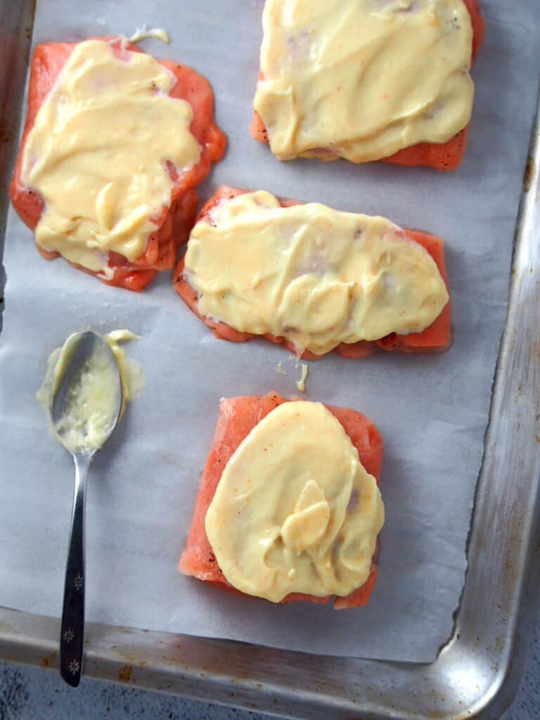 raw salmon fillets with tamarind-mayo topping on a parchment-lined baking sheet