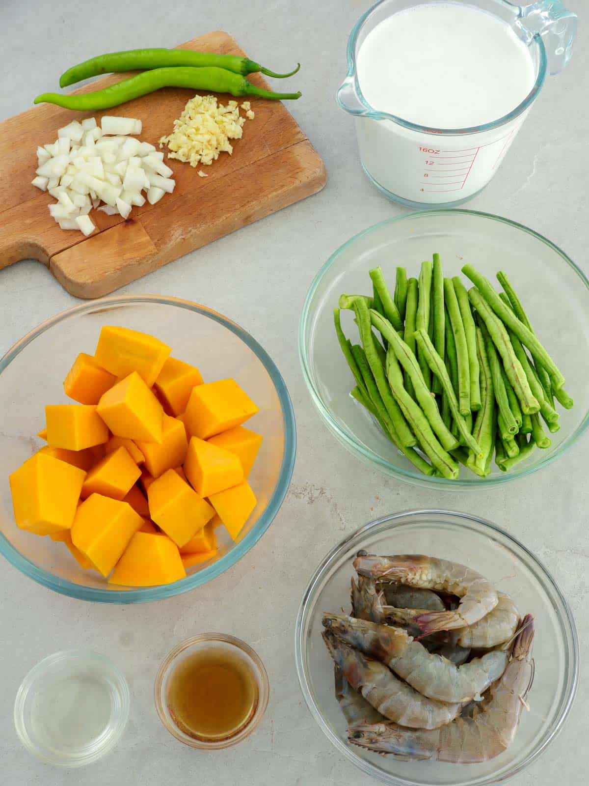 kabocha squash cubes, shrimp, cut long beans, chopped garlic, pepper, coconut milk, fish sauce, oil, chili peppers