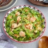 Ginisang Ampalaya at Hipon in a serving bowl with a plate of steamed rice and fried fish on the side