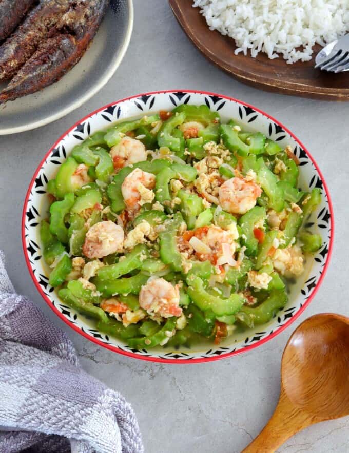 Ginisang Ampalaya at Hipon in a serving bowl with a plate of steamed rice and fried fish on the side