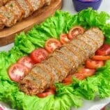 sliced Homemade Kikiam on a serving platter garnished with lettuce leaf and sliced tomatoes