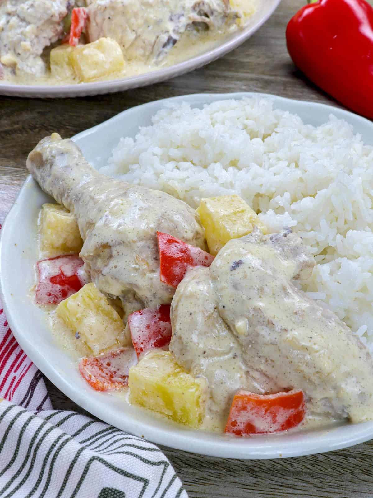 Filipino-style creamy chicken and pineapple stew on a white plate with steamed rice on the side.