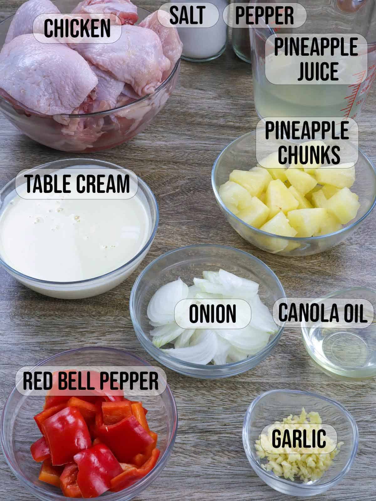 chicken, pineapple chunks, pineapple juice, table cream, red bell peppers, onions, oil, garlic in bowls.