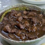 dinuguan in a serving bowl with a plate of steamed rice on the side