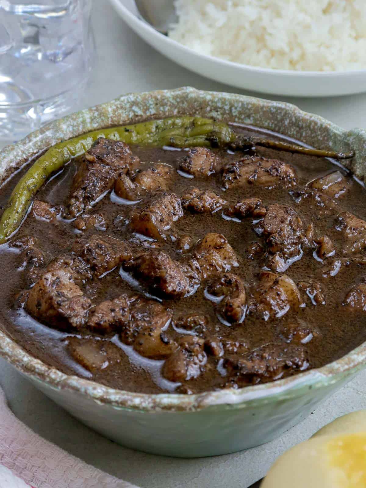 dinuguan in a serving bowl with a plate of steamed rice on the side